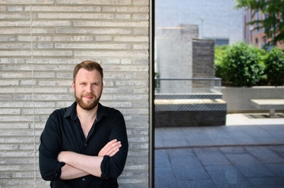 Felix Heide standing outside in front of a building with gray brick and glass