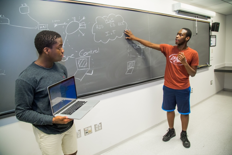 Students  talking at the chalkboard.